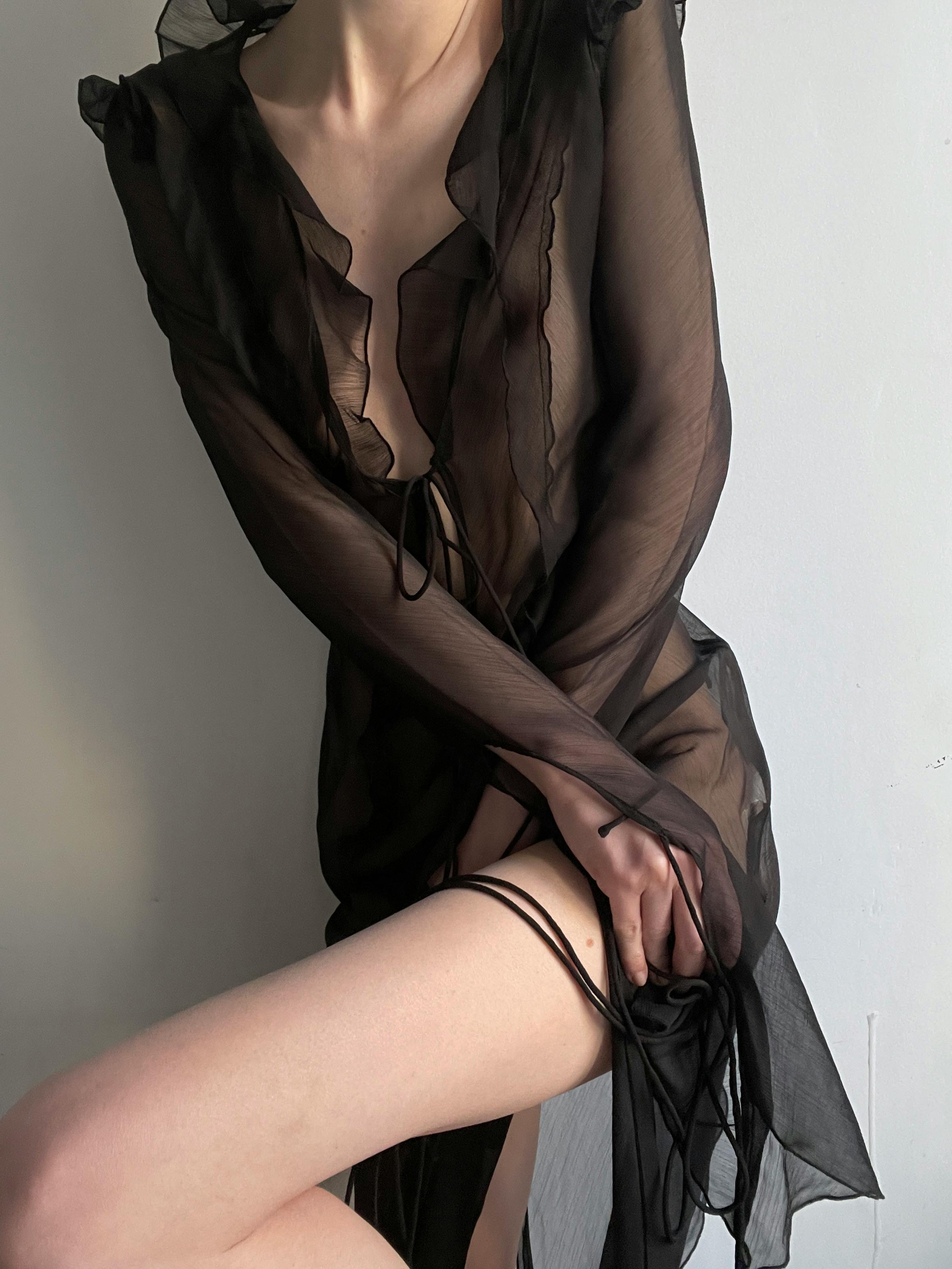 Person wearing a sheer black dress with long sleeves and a skirt.