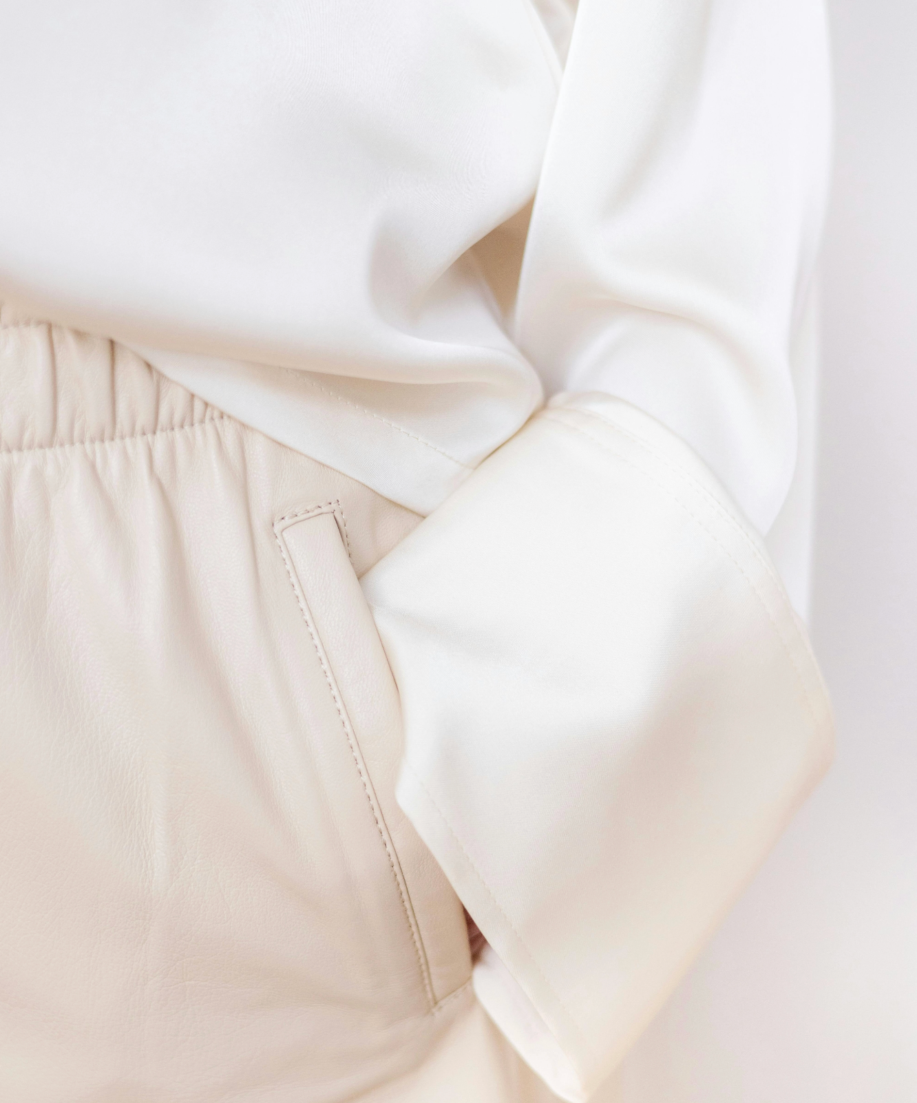 Close-up of beige pants with a white sweater on a light background