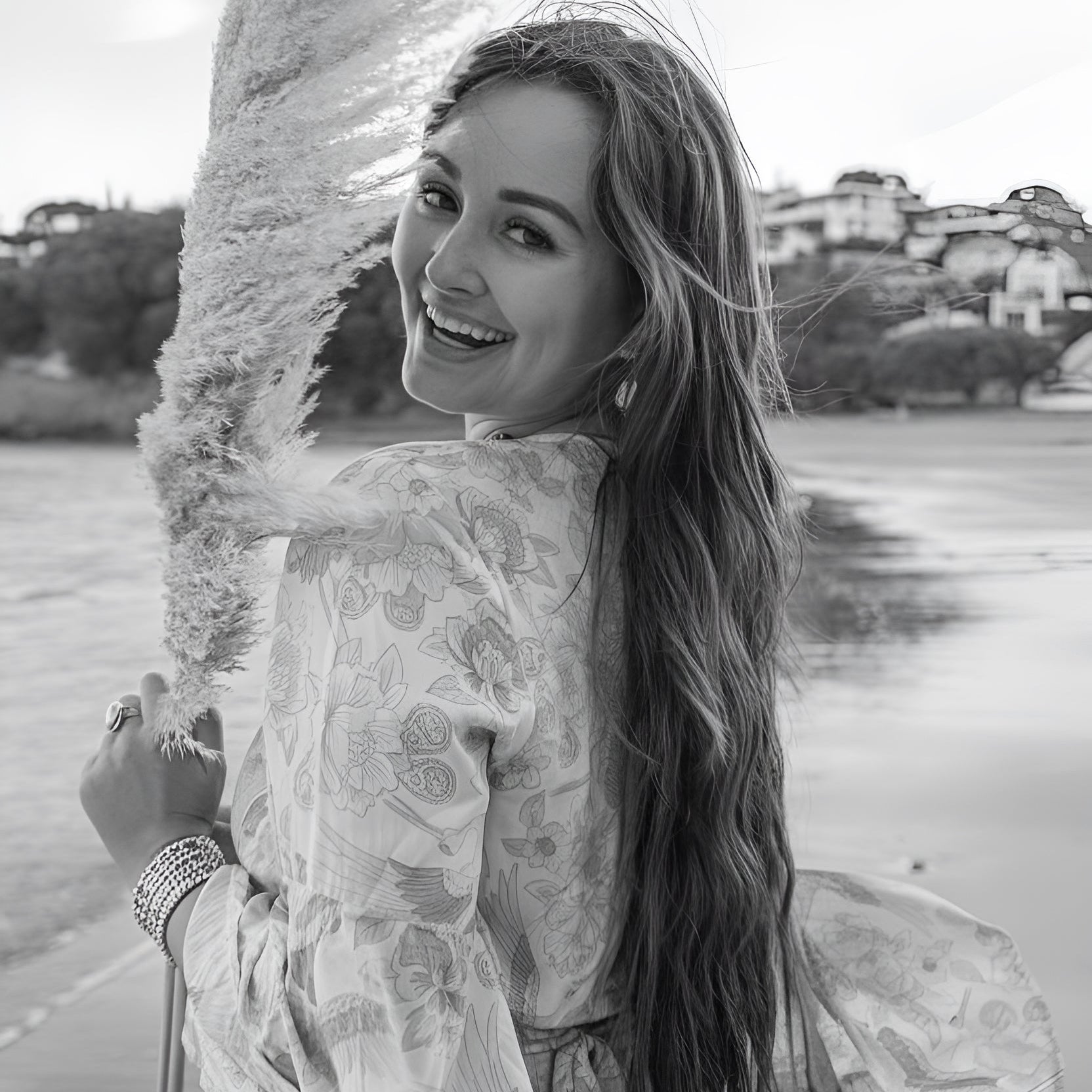 Woman with long hair standing by a lake with a scenic background